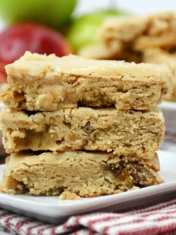 Apple blondies stacked on a white plate.