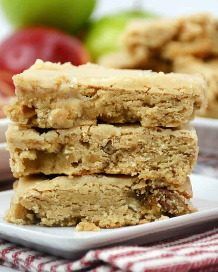 Apple blondies stacked on a white plate.