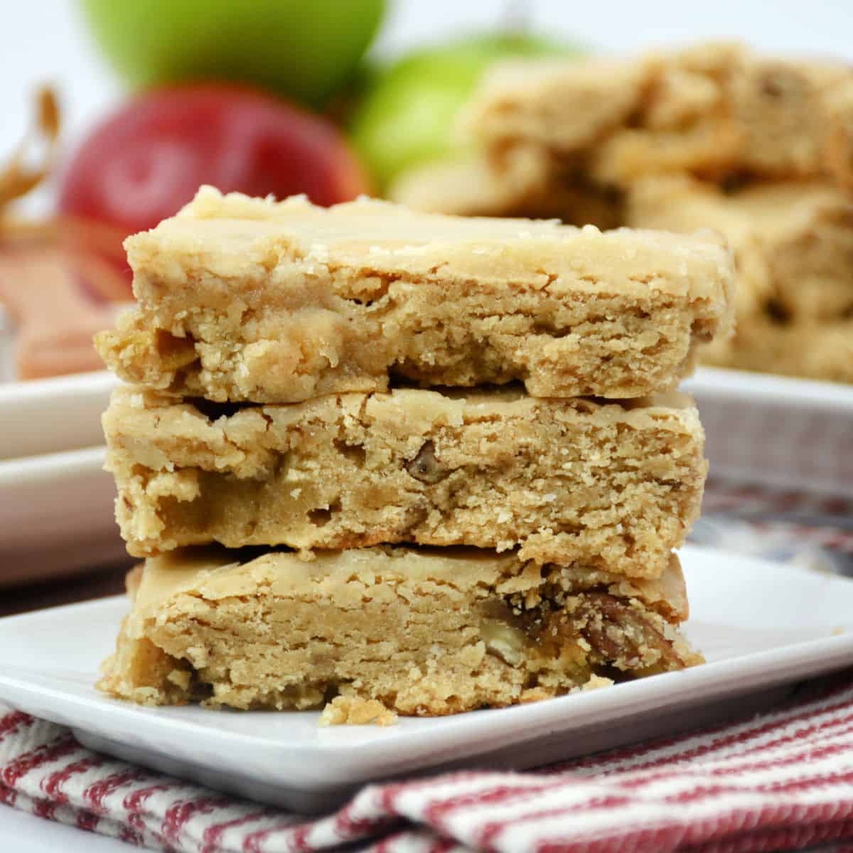 Apple blondies stacked on a white plate.