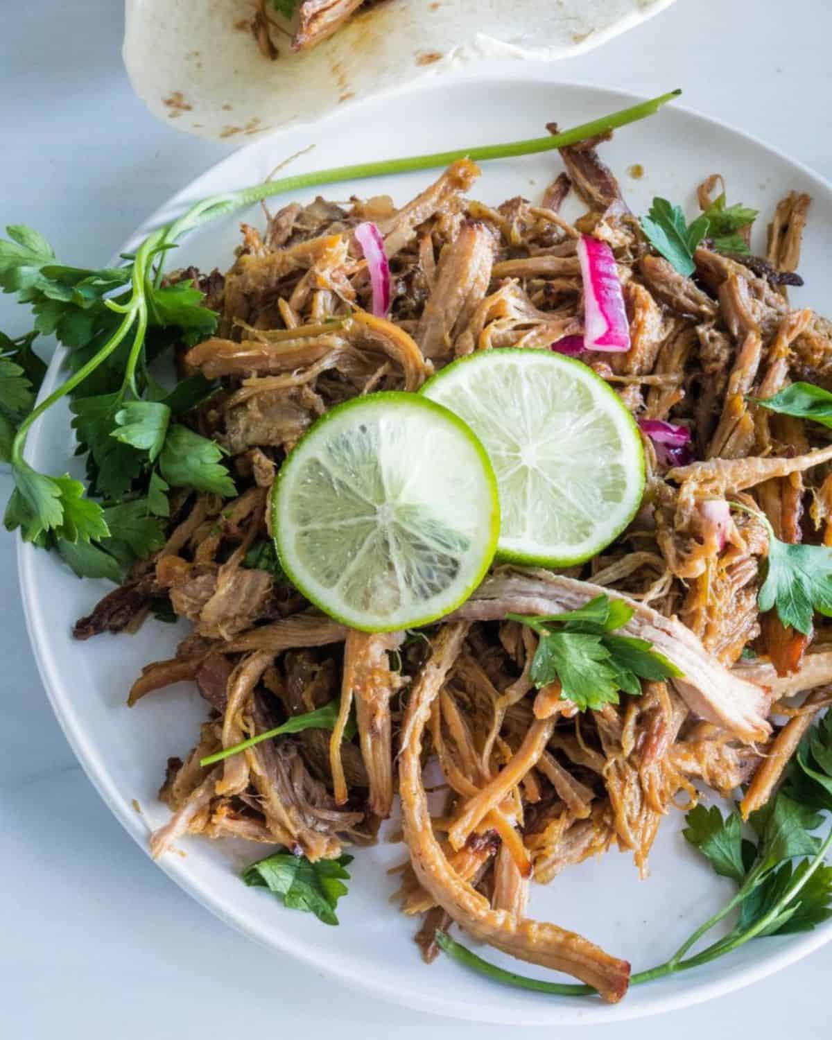 Pork canita meat shredded on a white plate to make carnitas. 