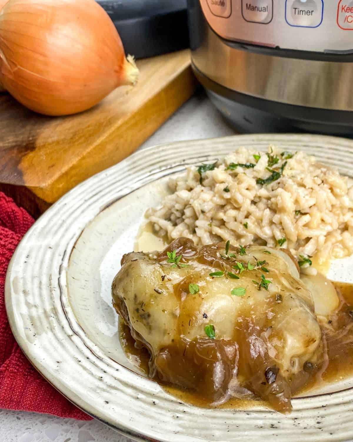 A white plate with french onion chicken and rice on the plate.