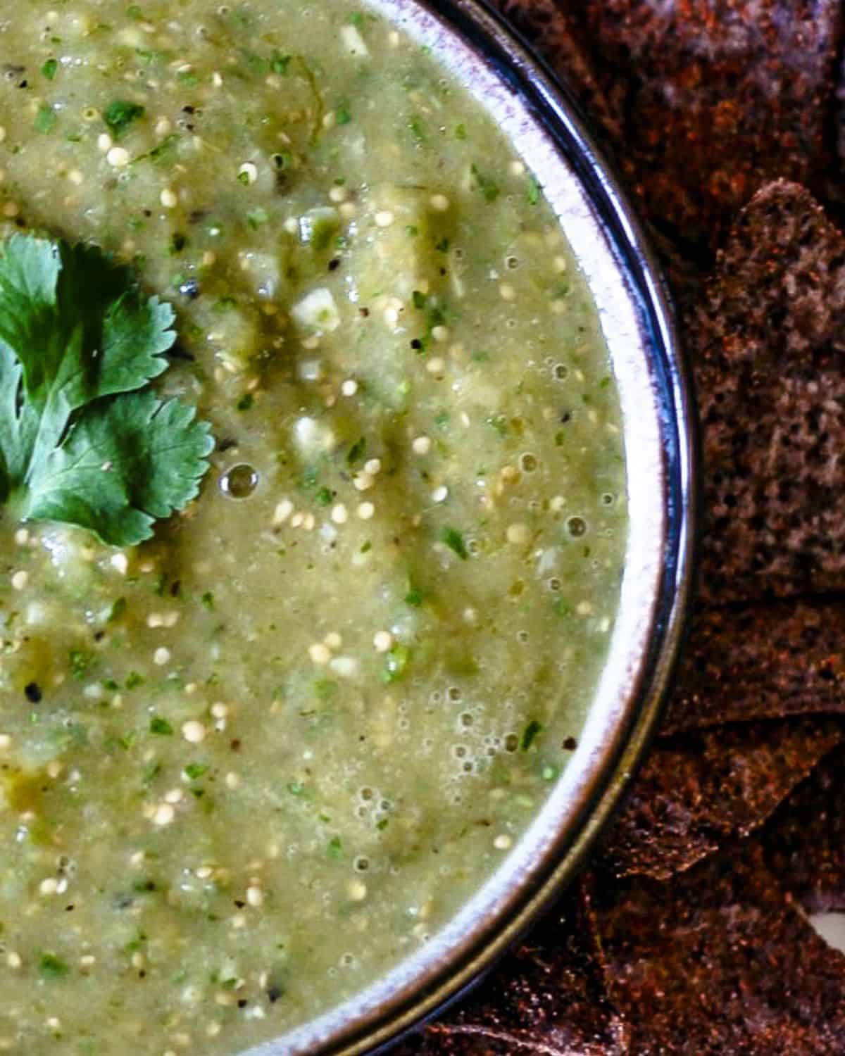 A bowl of green salsa verde with chips on the side.