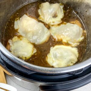 Four pieces of chicken in an Instant Pot with brown gravy.