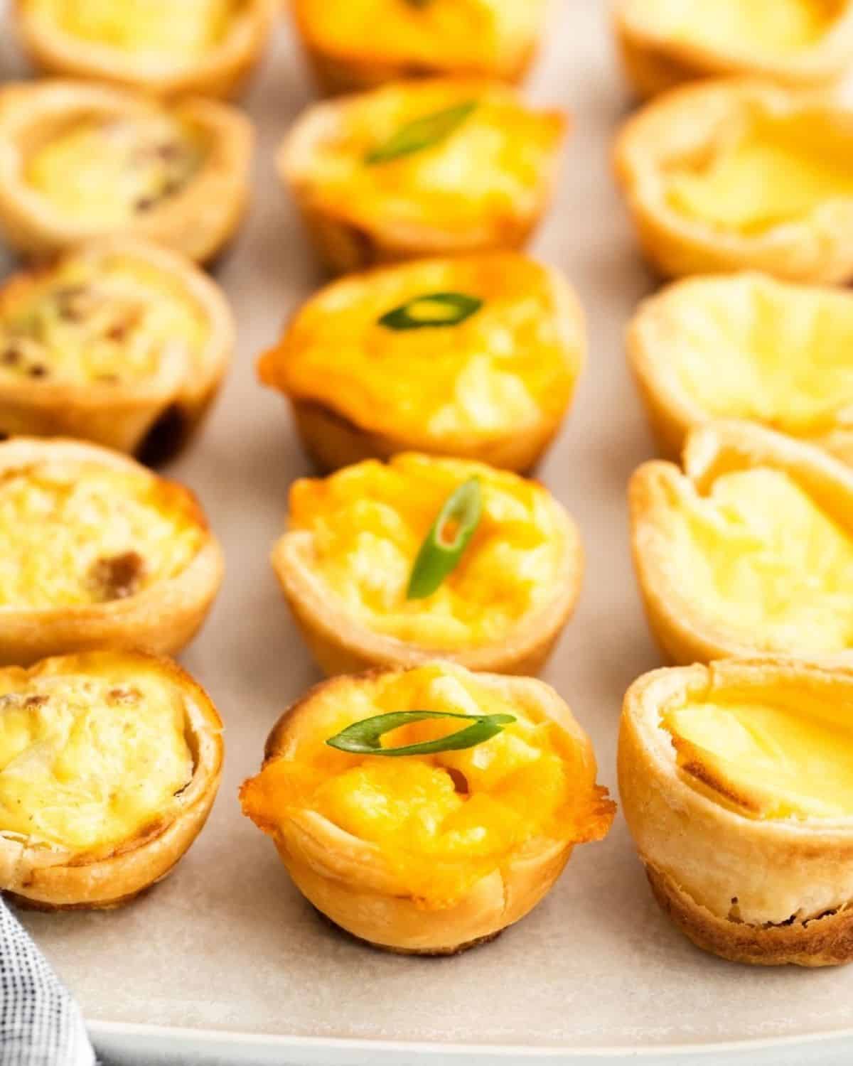 A tray of mini quiche on a white counter.