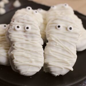 Cookies decorated as mummies on a plate.