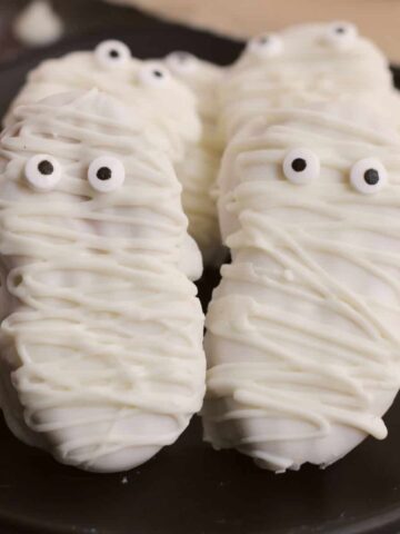 Cookies decorated as mummies on a plate.