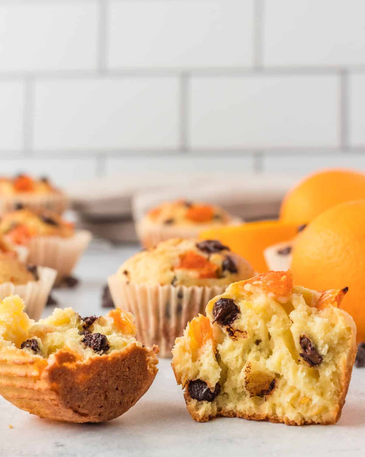 Orange muffins split open on a white table.