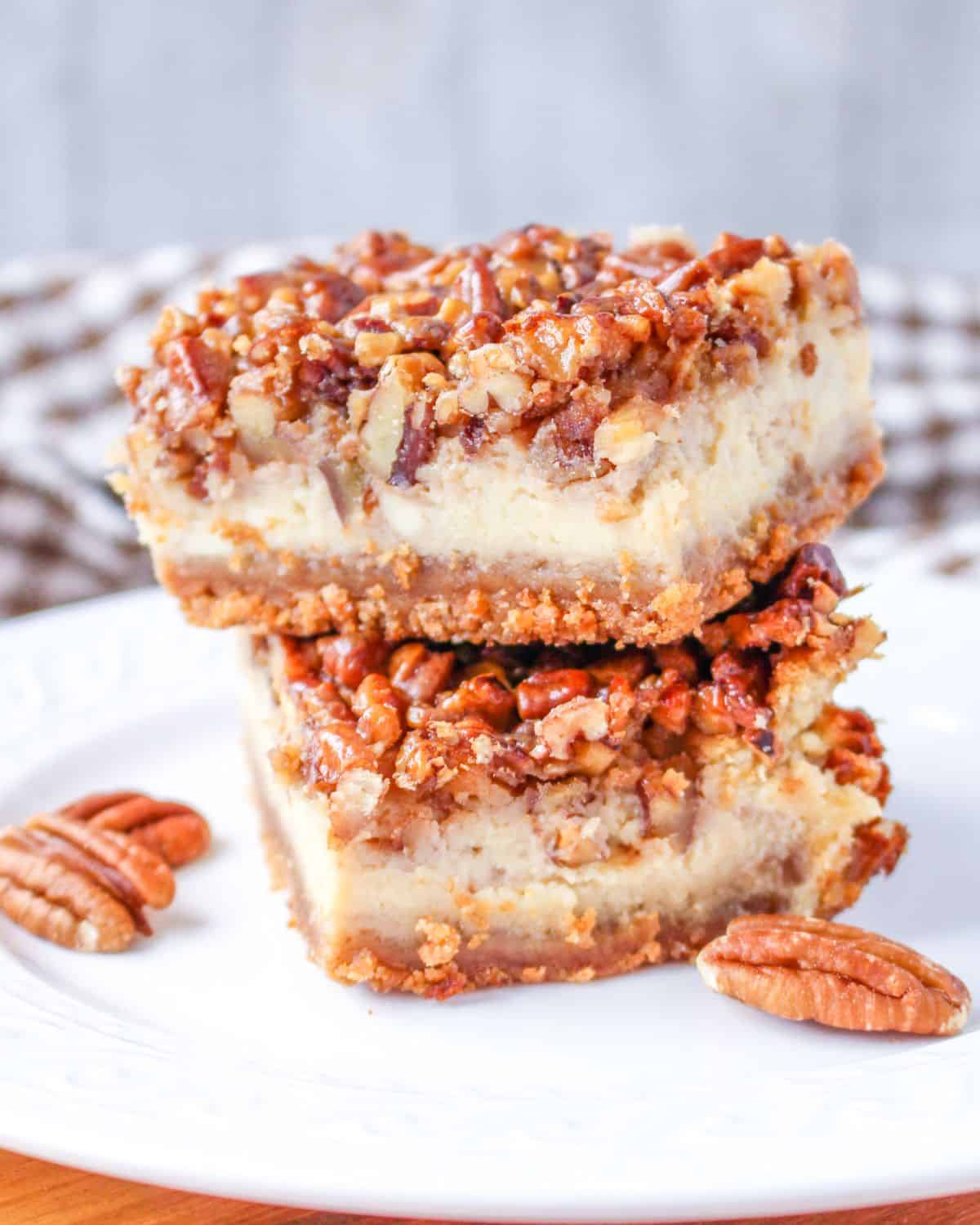 Pecan Pie Cheesecake bars stacked up on a plate. 