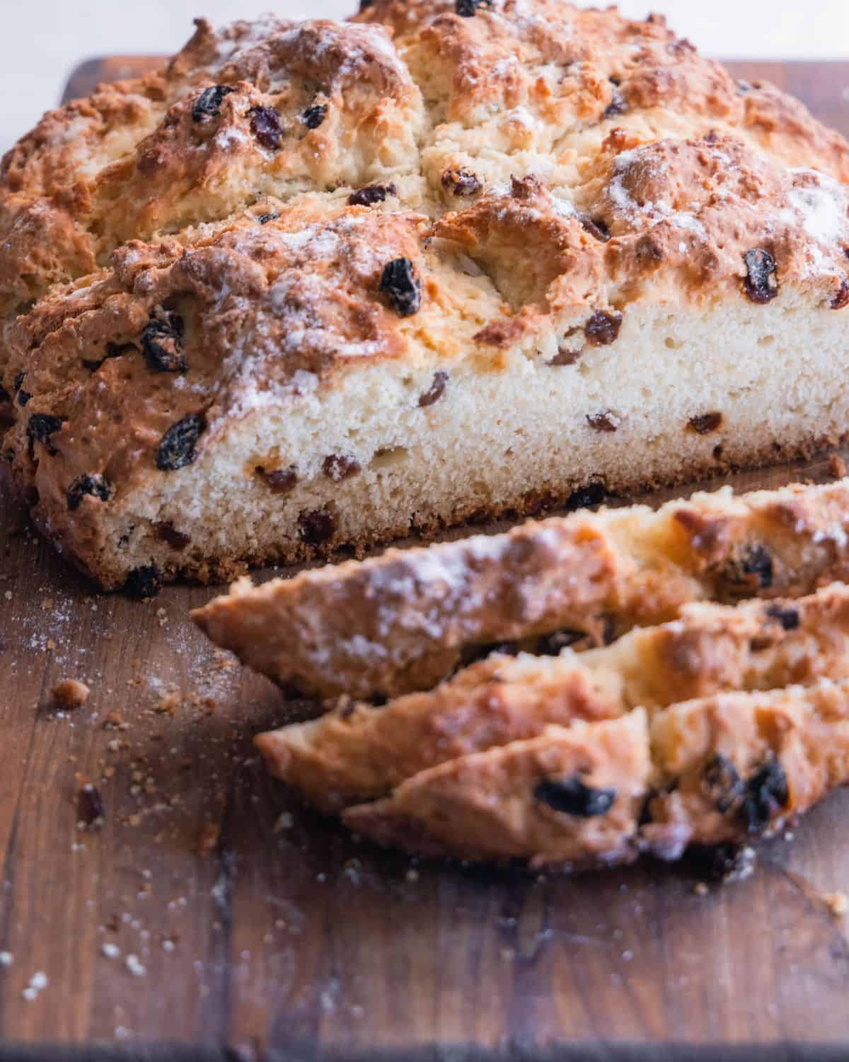 A sliced baked bread with raisins on a cutting board.