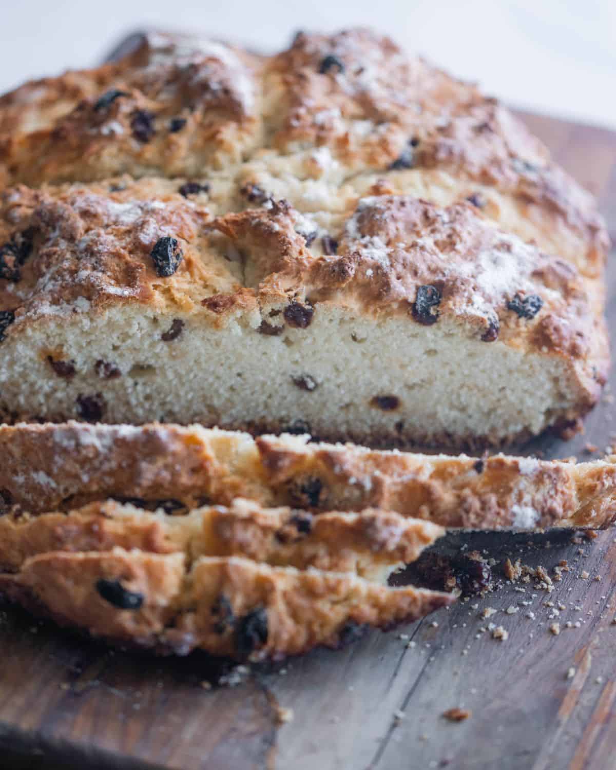 Sliced Irish soda bread with raisins on a cutting board.