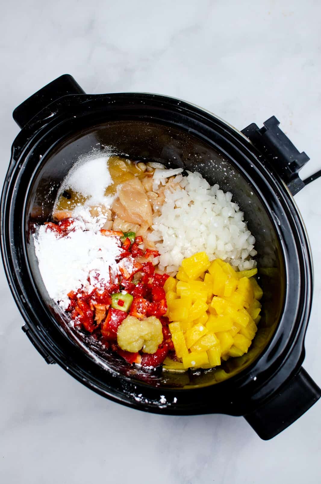 A slow cooker filled with ingredients to make sweet and sour chicken.