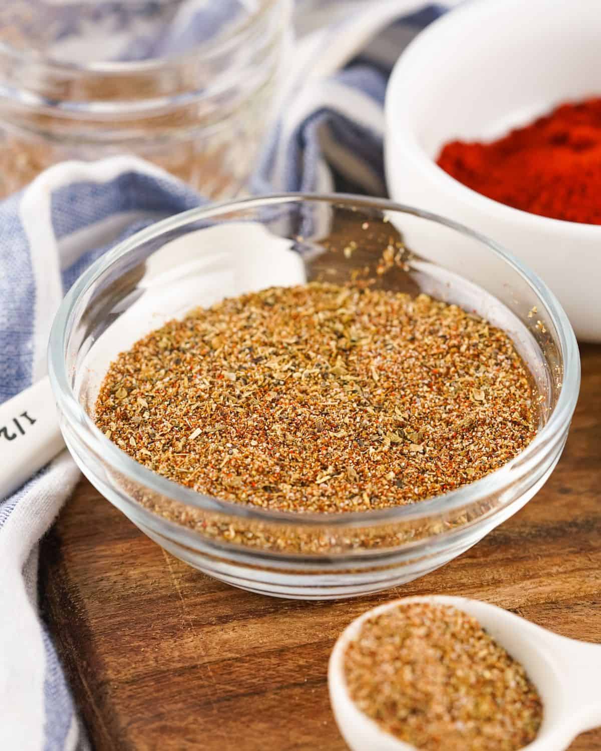 A glass bowl filled with seasoning on a wooden board.