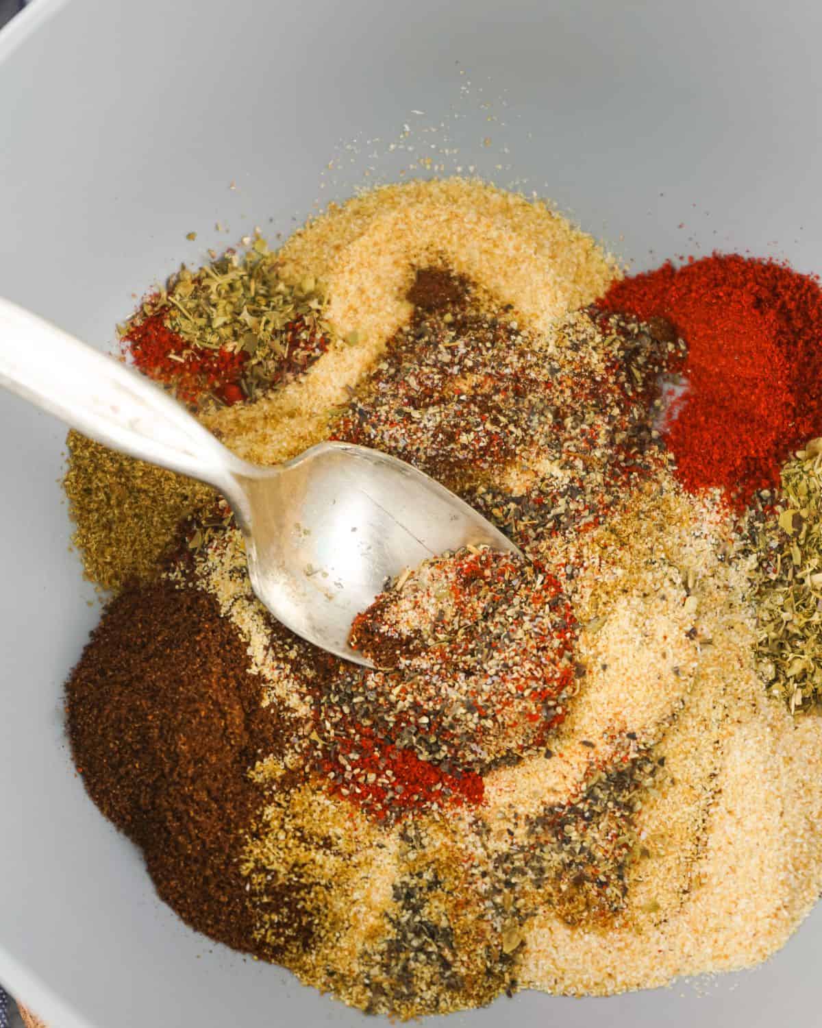 Spices being mixed together in a bowl with a spoon.