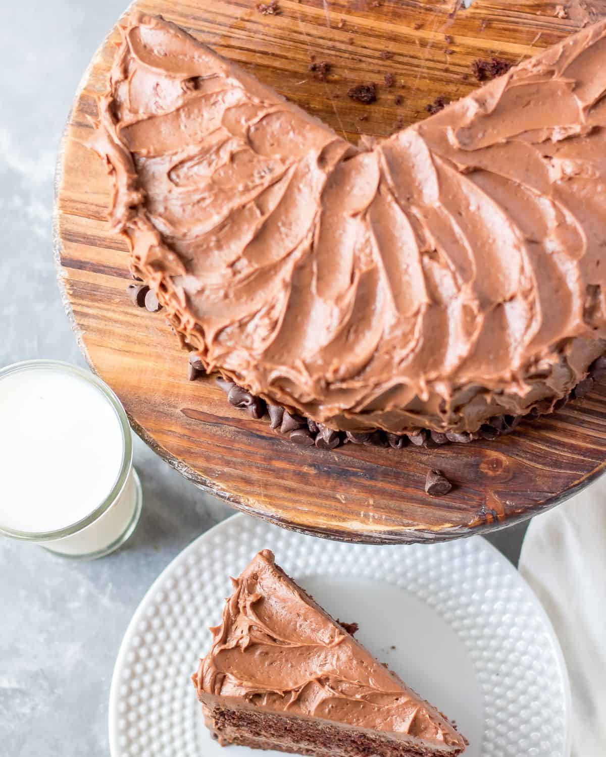 Homemade chocolate cake with chocolate frosting sliced and on a cutting board. 