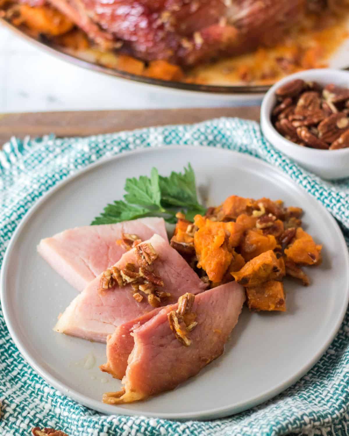 A plate of baked ham topped with pecans 