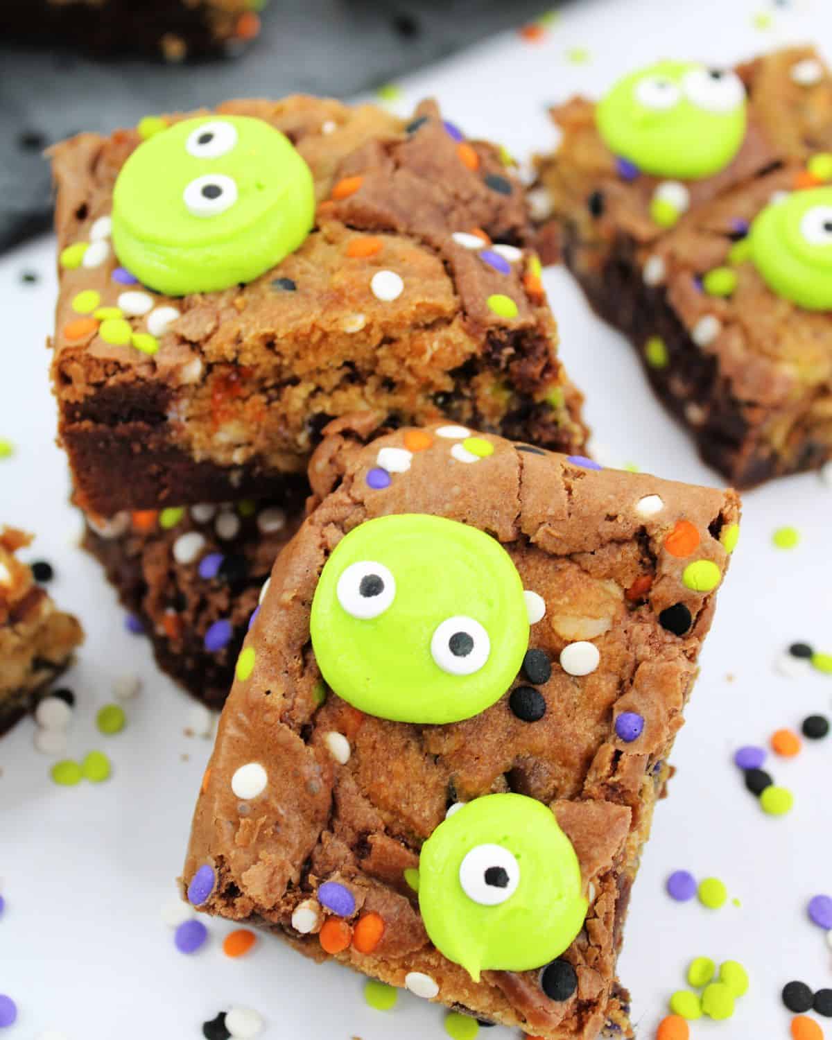 Halloween Monster Brownies on a plate with neon green faces with eyes on top of the brownies. 