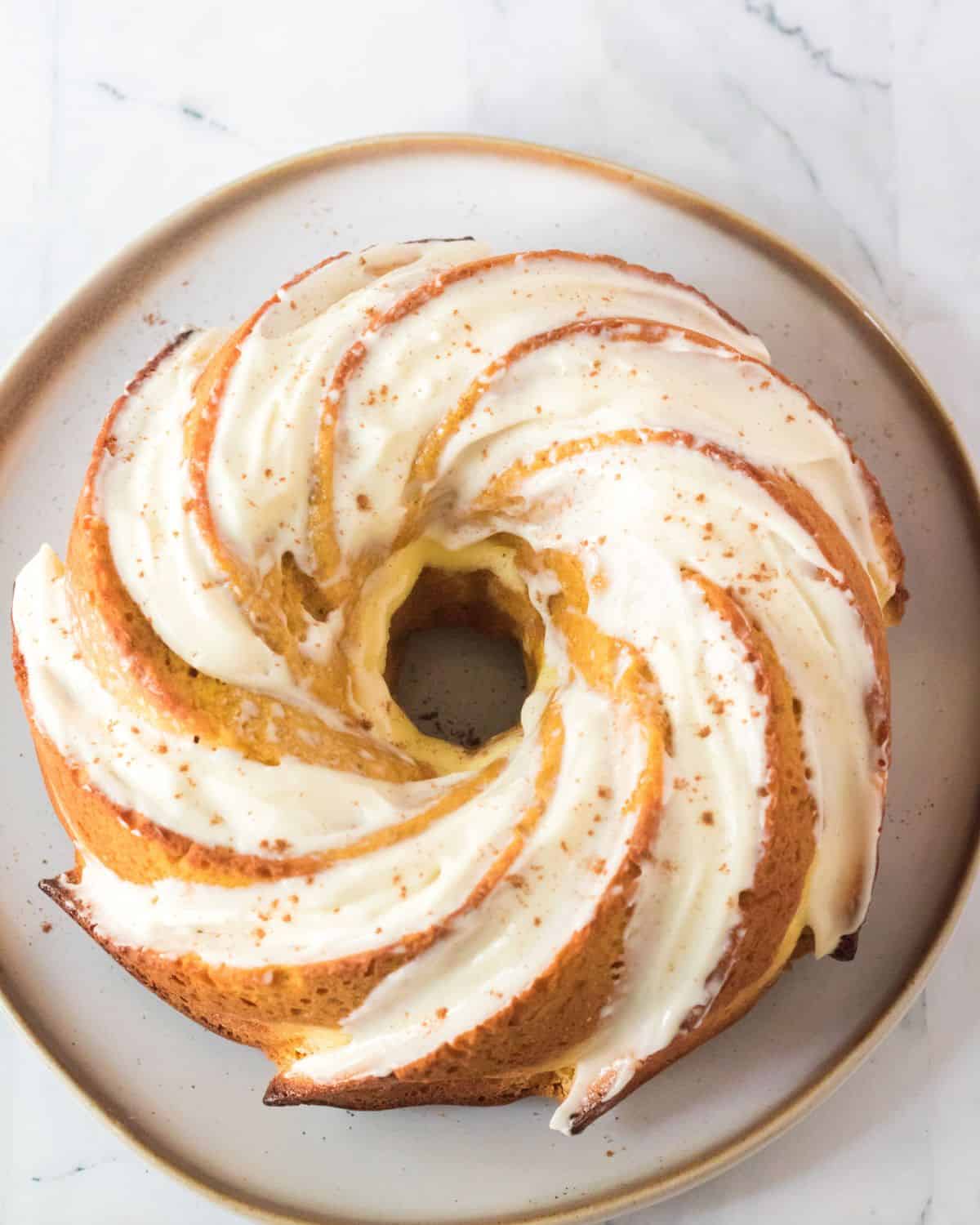 An overhead view of a bundt cake with a cream cheese frosting.