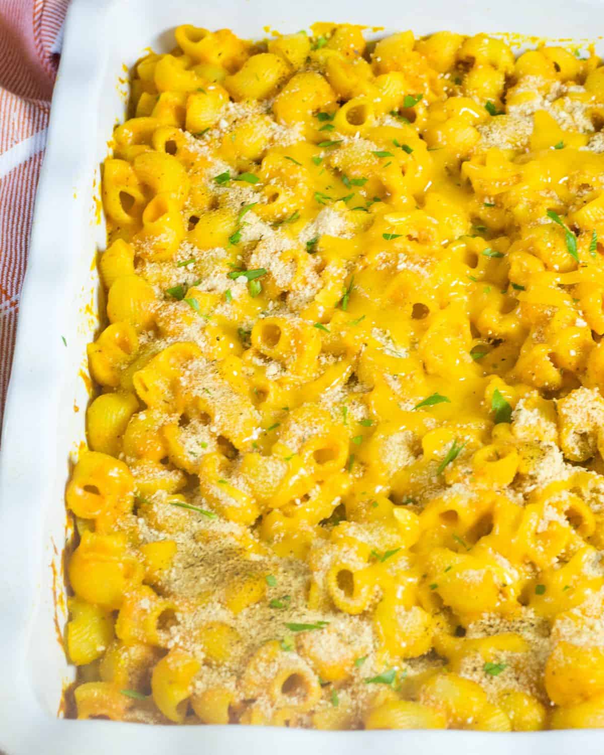 A white casserole dish with baked pumpkin mac and cheese topped with Panko breadcrumbs