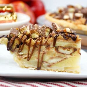 A side view of a slice of apple pie topped with twix bar drizzle.