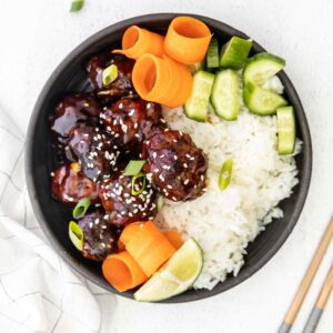 An overhead shot of asian style meatballs with rice and veggies.