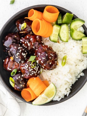 An overhead shot of asian style meatballs with rice and veggies.