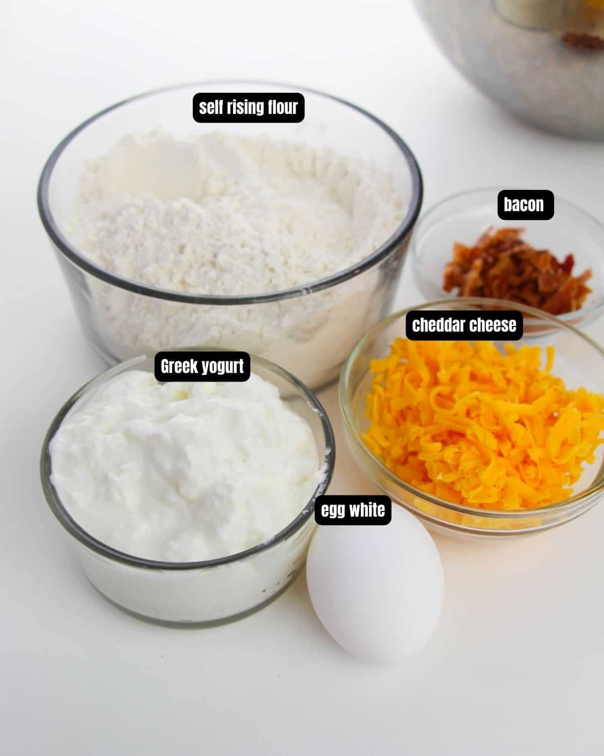 Ingredients with text overlay to make cheddar bacon bagels with yogurt.