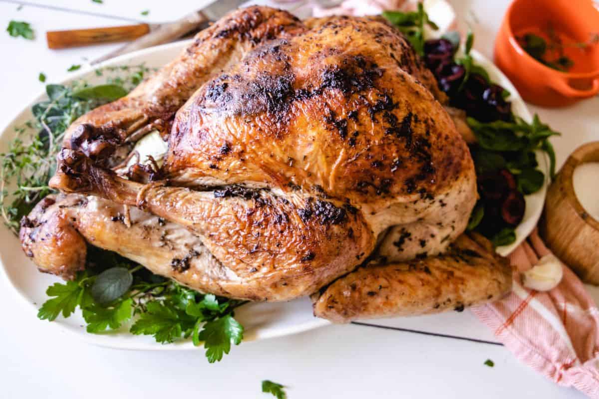 An oven roasted turkey on a platter with fresh herbs 