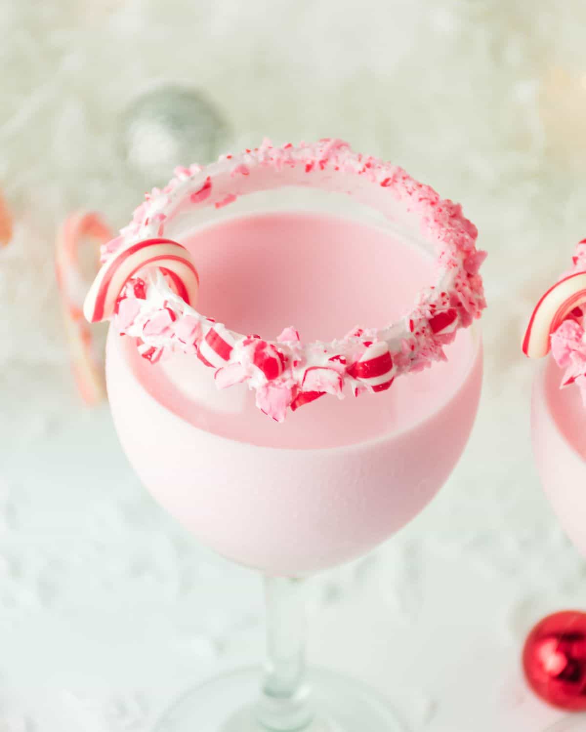 A peppermint cocktail with a candy cane trim and mini candy canes. 