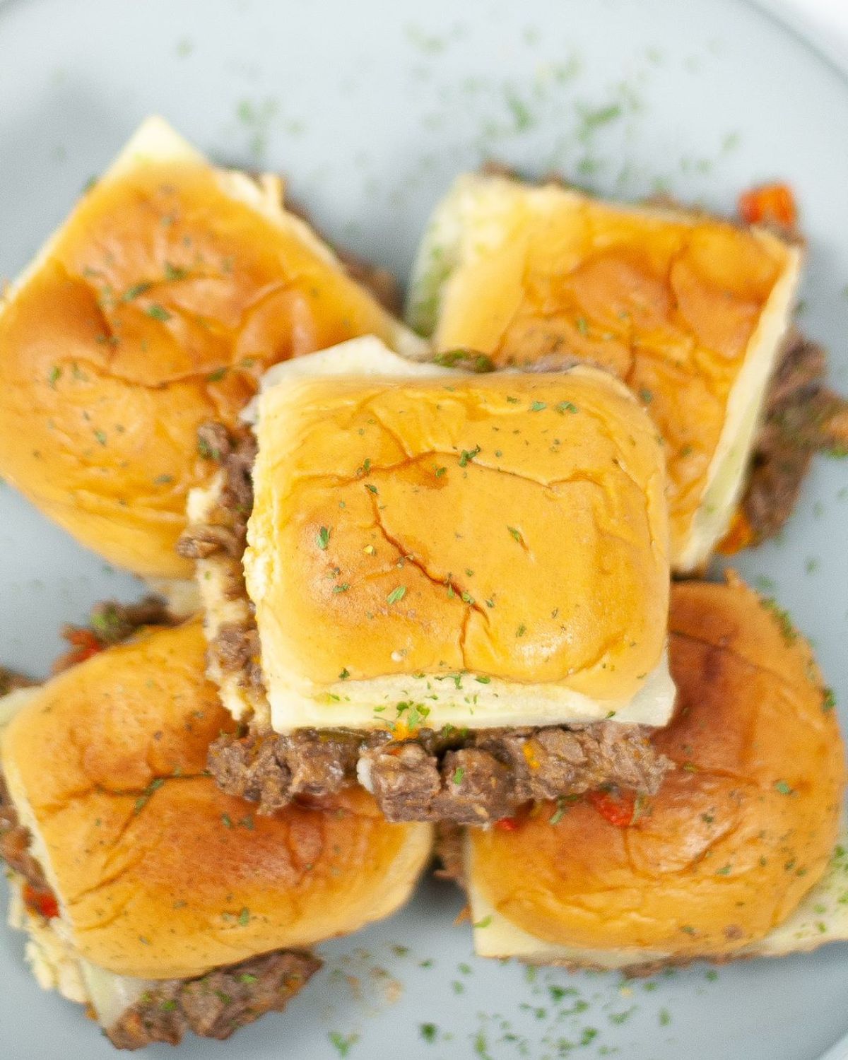 An overhead view of Philly cheesesteaks on a grey plate.