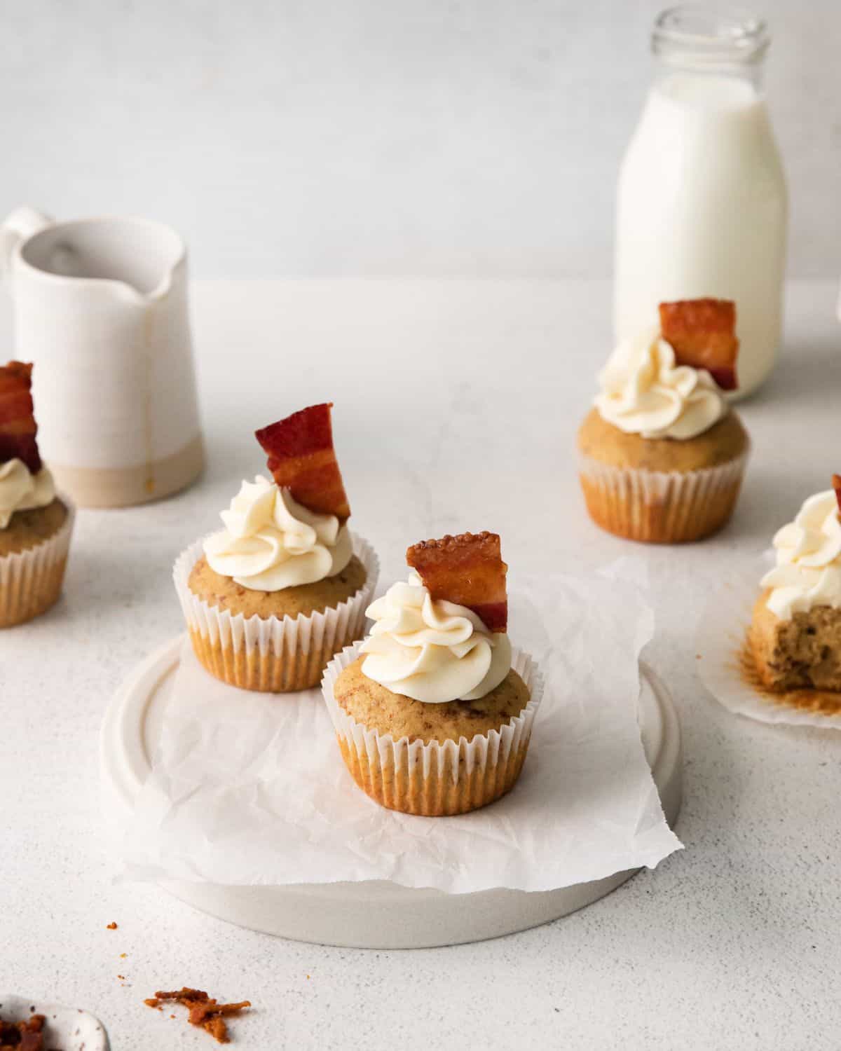Maple Cupcakes with a maple buttercream frosting and candied bacon on a plate. 