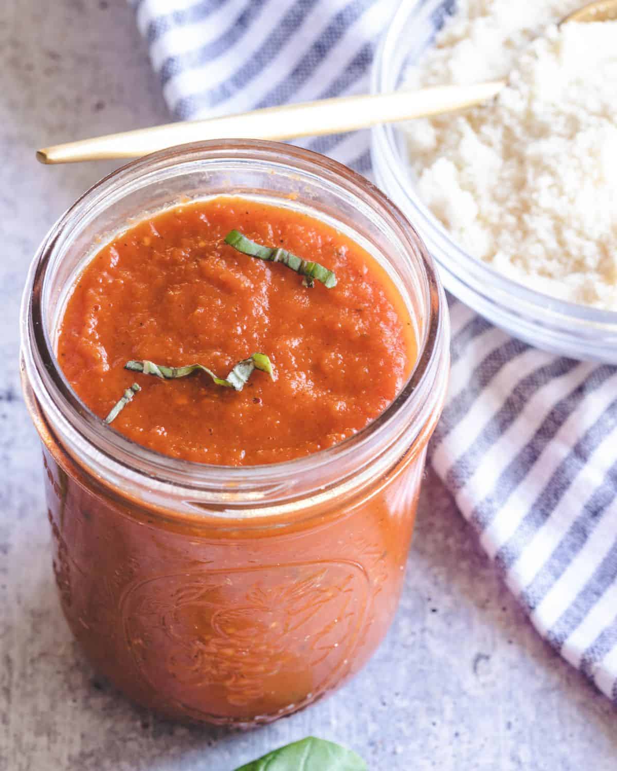 Homemade marinara sauce in a mason jar topped with chopped basil.