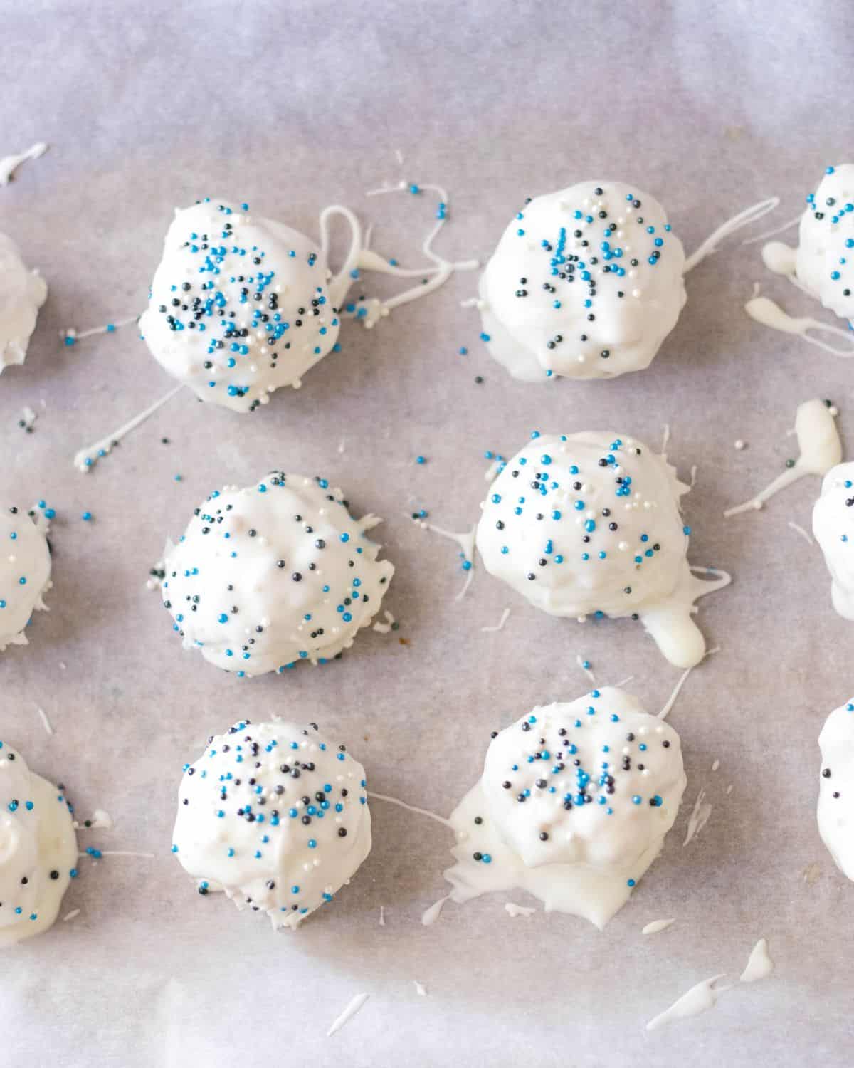 Peanut Butter Balls decorated with white chocolate and sprinkles on a large plate.