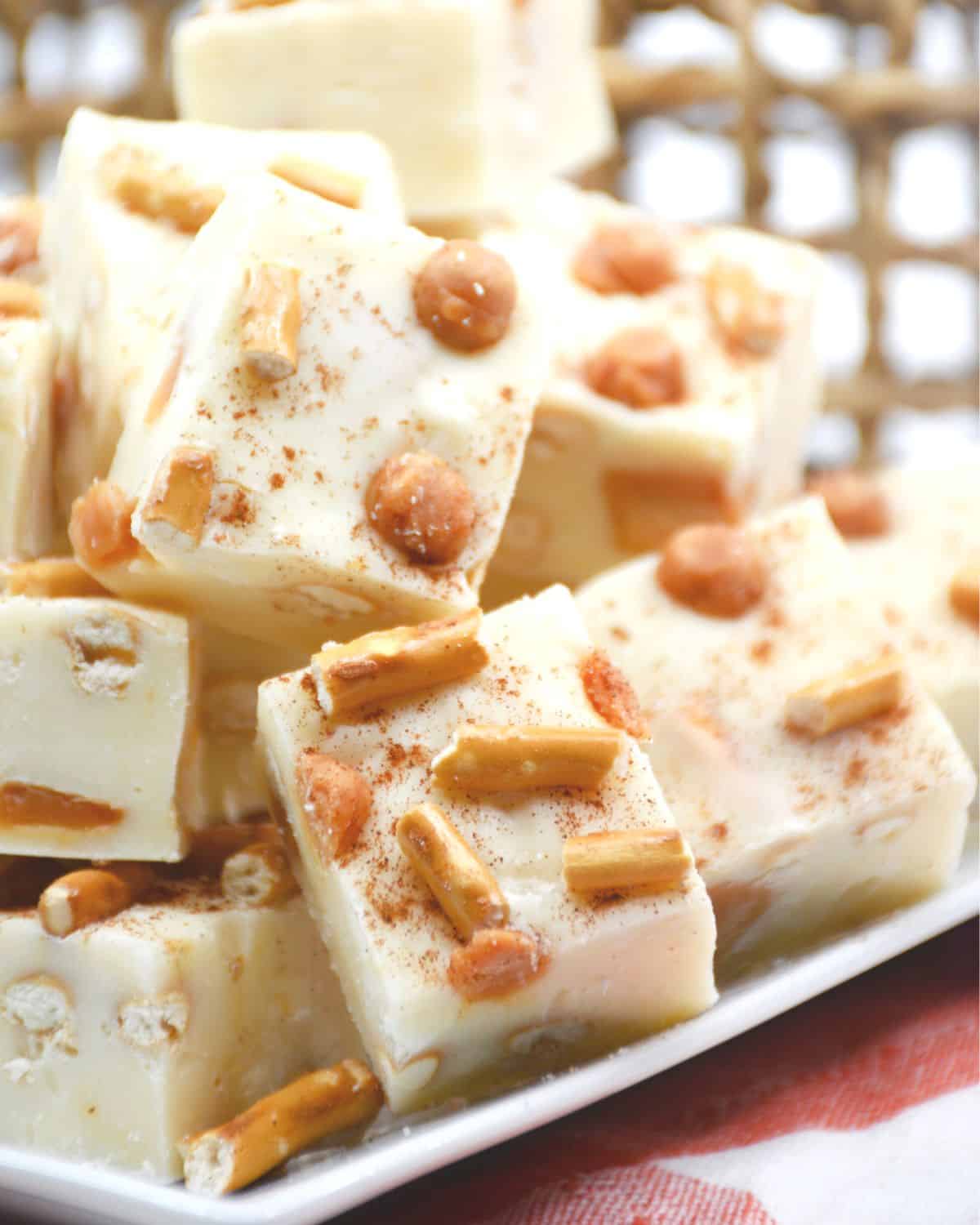 White chocolate fudge with caramel bits and pretzel pieces on a plate.