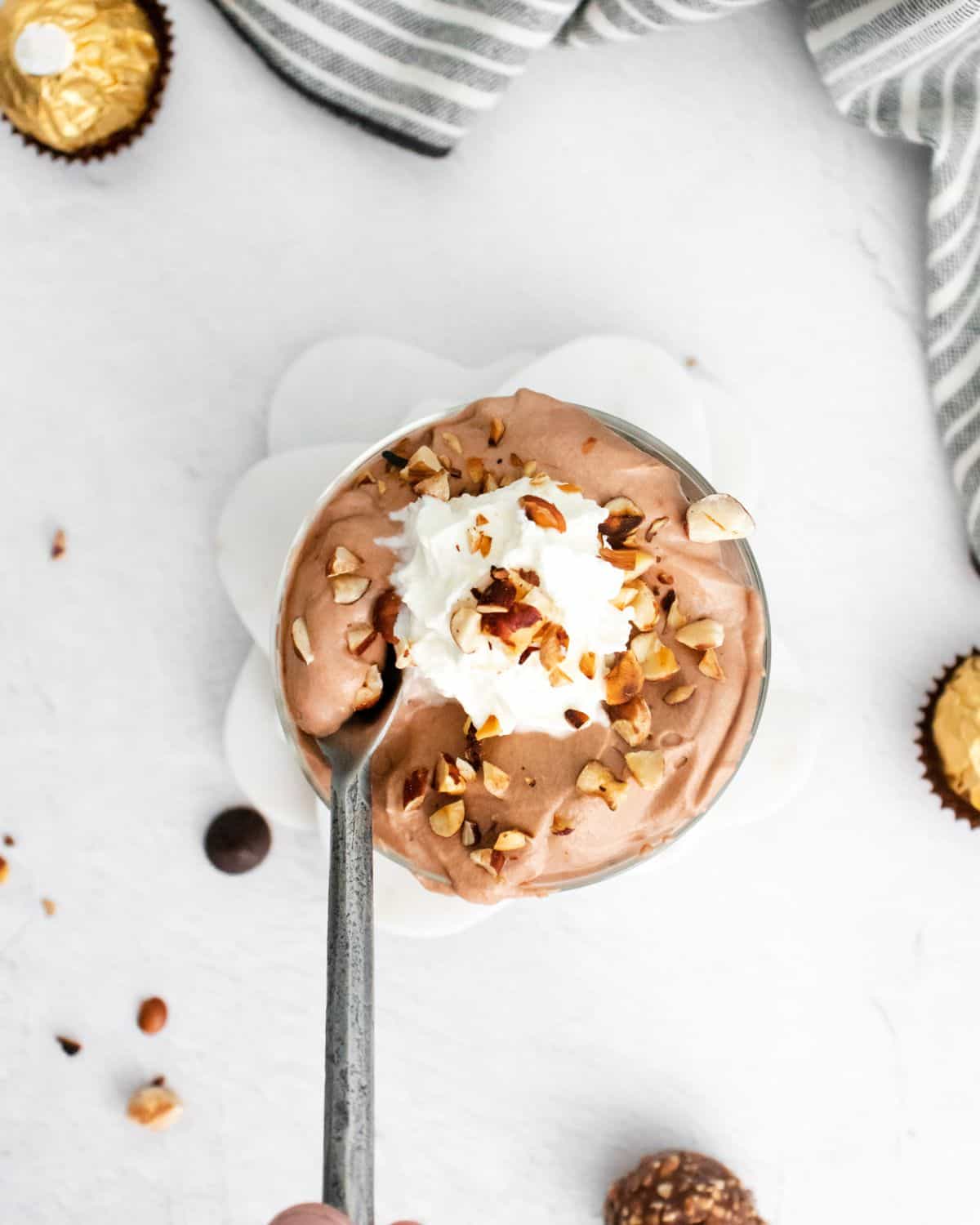 An overhead view of brownie chocolate trifle topped with hazelnuts and whipped cream.