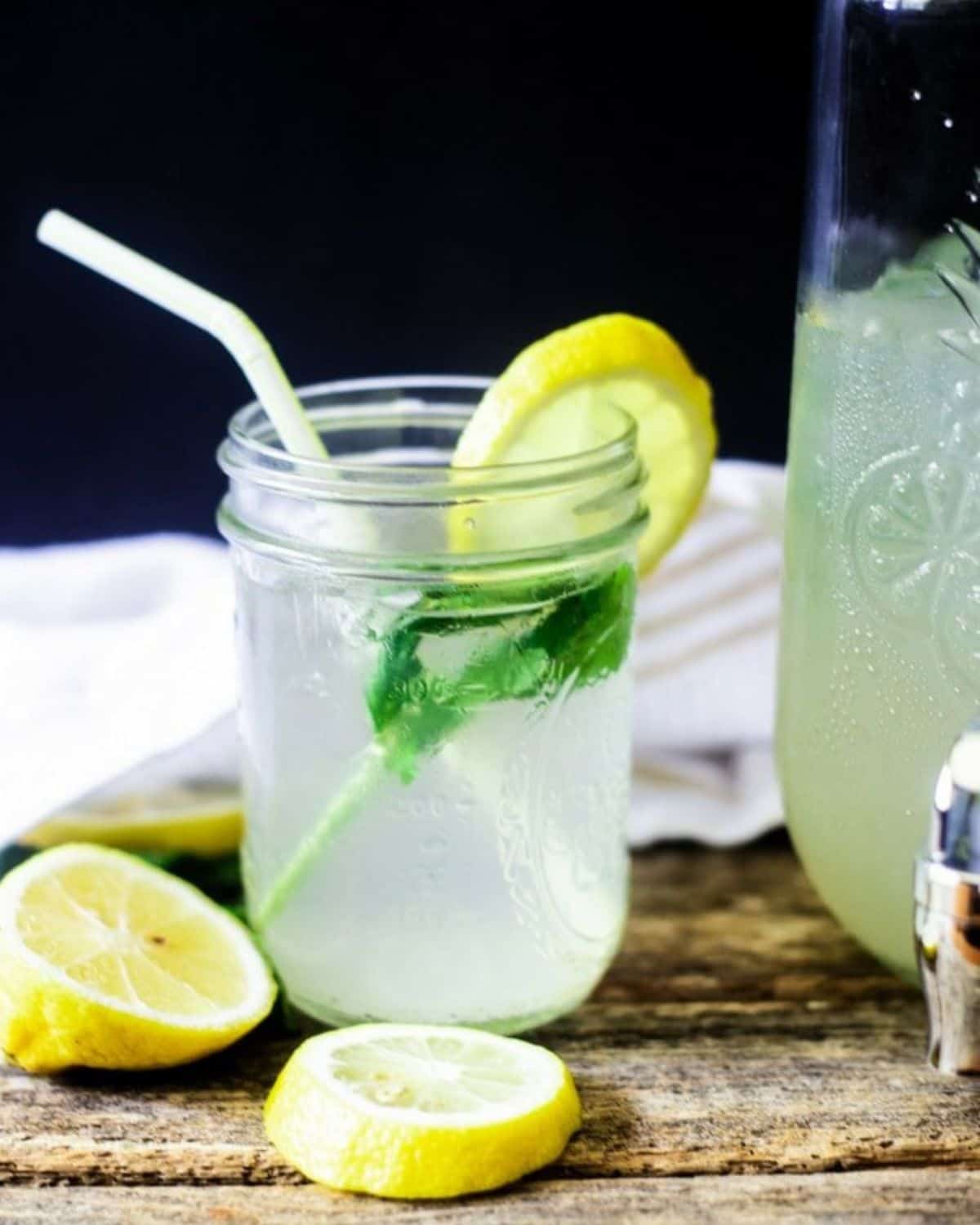 A mason jar filled with lemonade, ice, mont, and lemons.