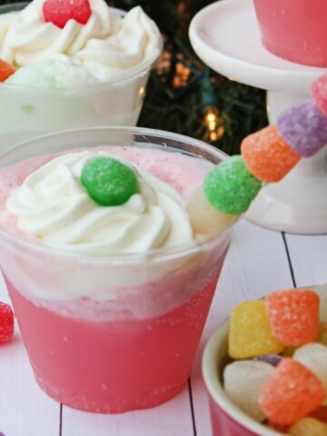 A glass of sherbet punch topped with whipped cream and gumdrops.