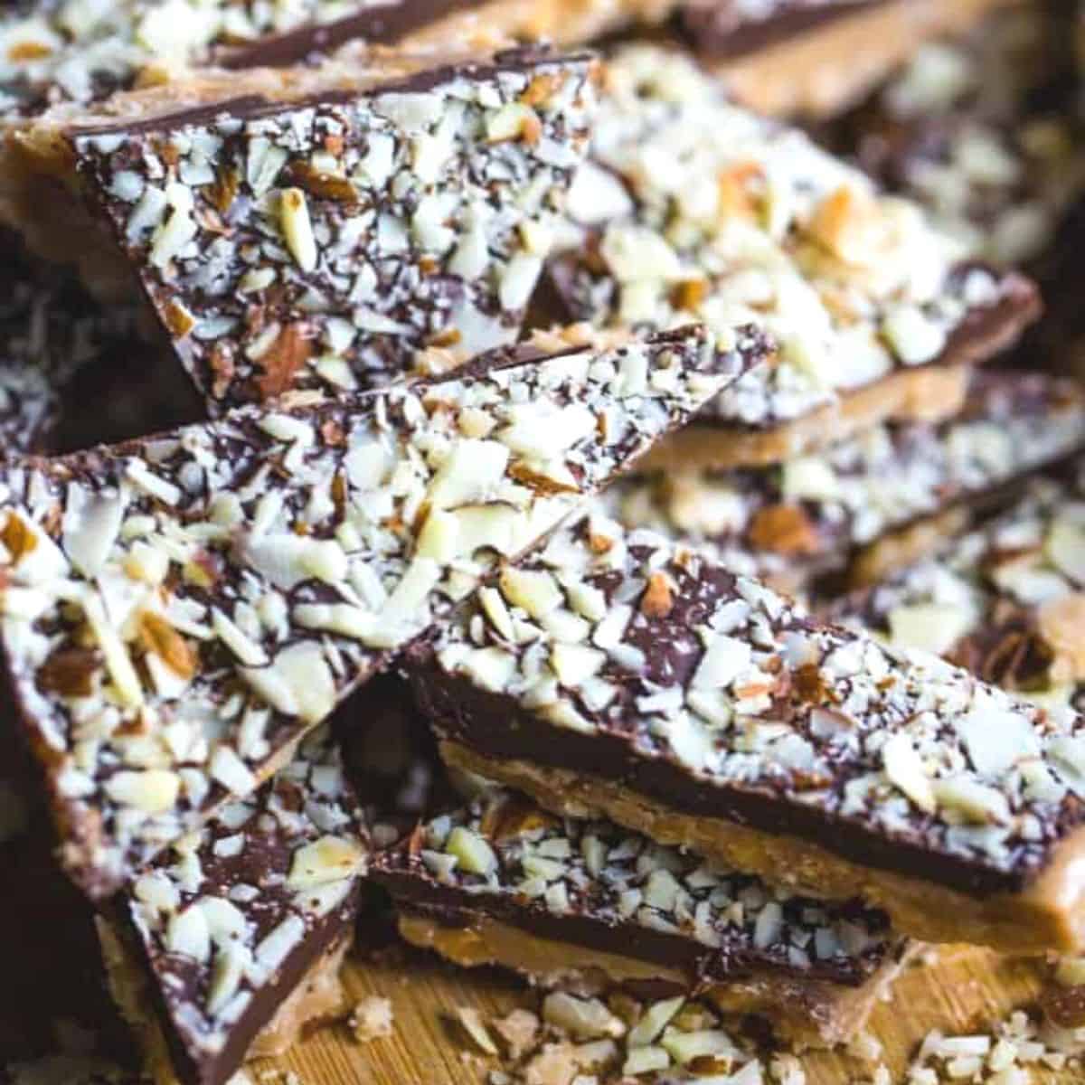 Pieces of almond roca topped with chopped almonds.