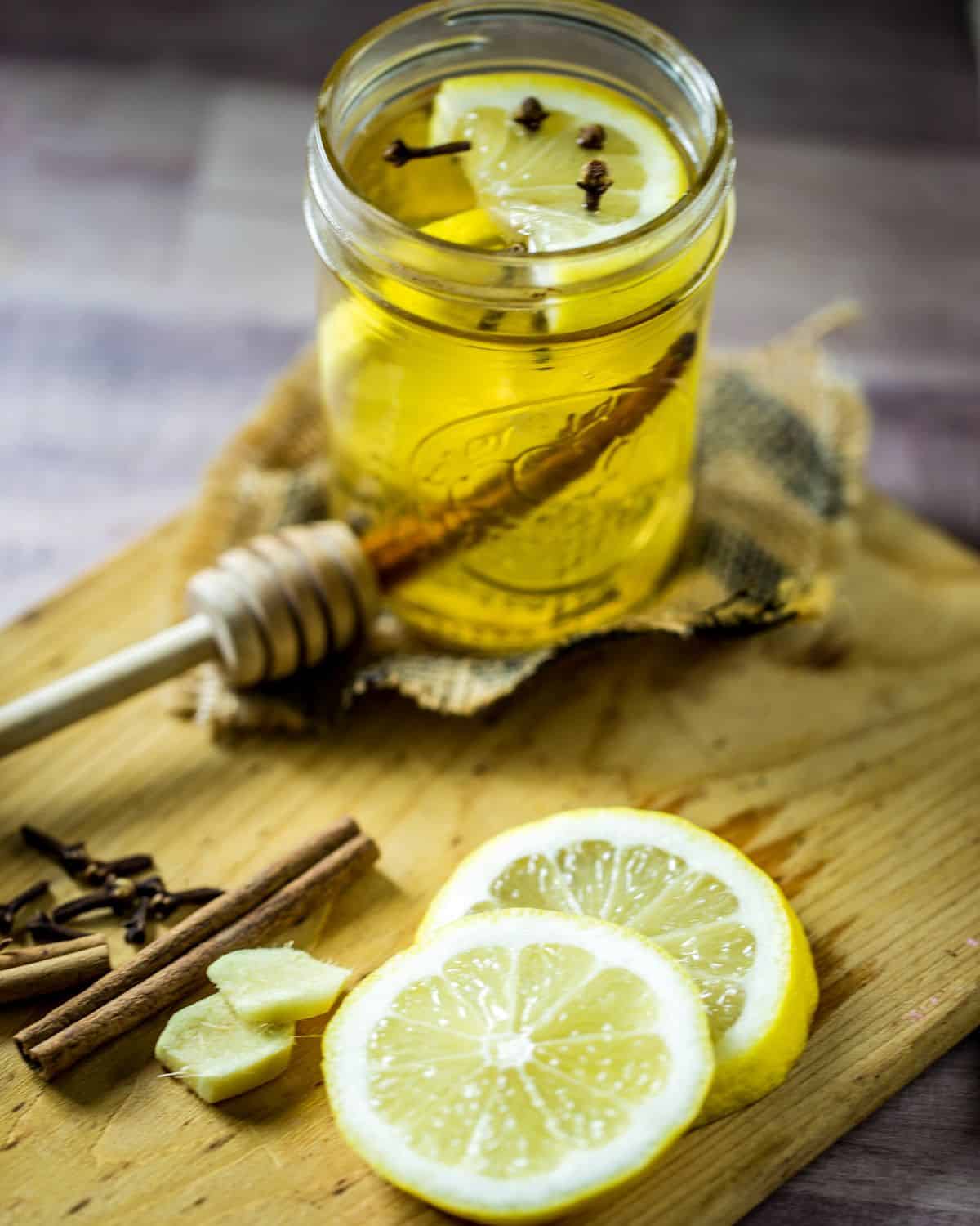 Hot toddy cloves, whiskey, lemon slices on a board.