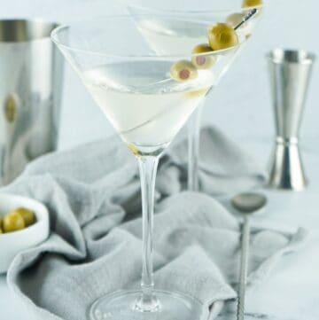 A martini with 3 olives in a glass.