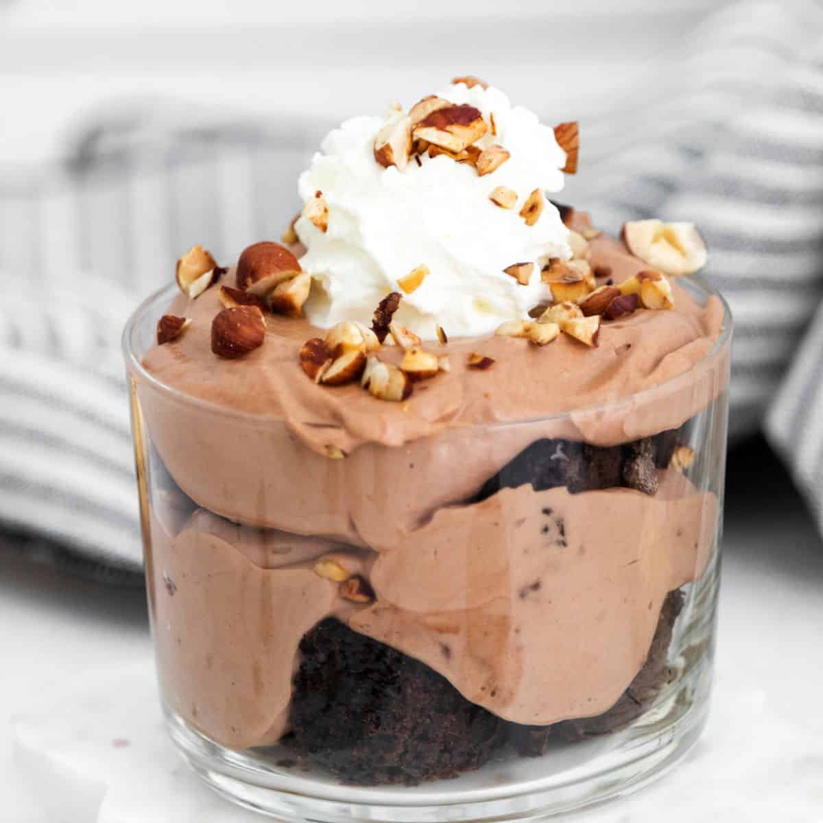 Brownie Trifle with chocolate nutella whipped cream in a glass bowl.