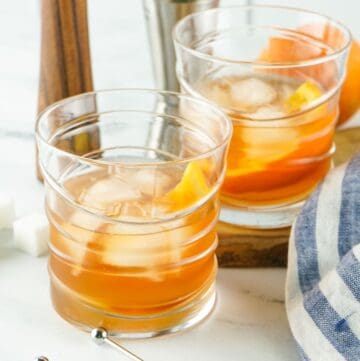 Two old fashioned cocktails in glasses.