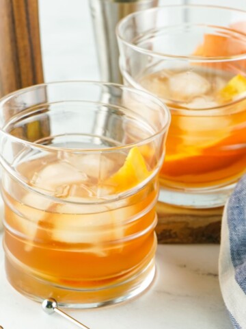 Two old fashioned cocktails in glasses.