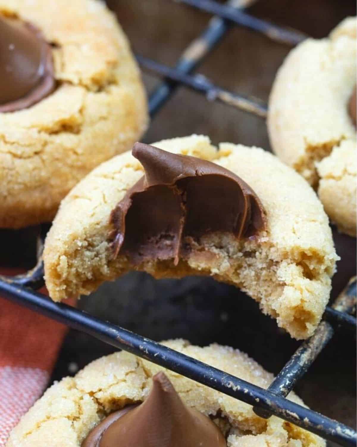 Peanut Butter Blossoms Cookie Recipe cookie bitten into on a wire rack.