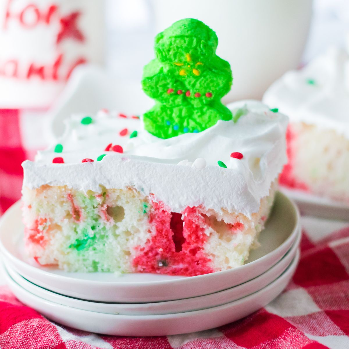 A white poke cake with red and green jello topped with a green peep.