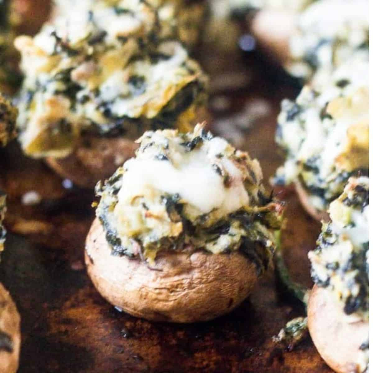 Spinach artichoke stuffed mushrooms on a baking tray.