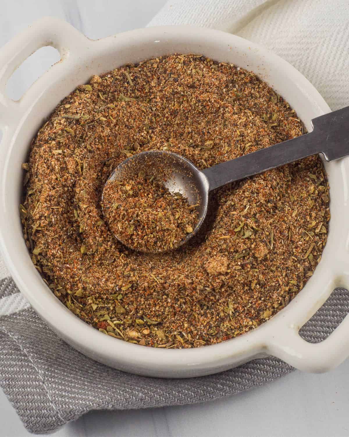 A bowl of homemade cajun seasoning with a teaspoon in the bowl.