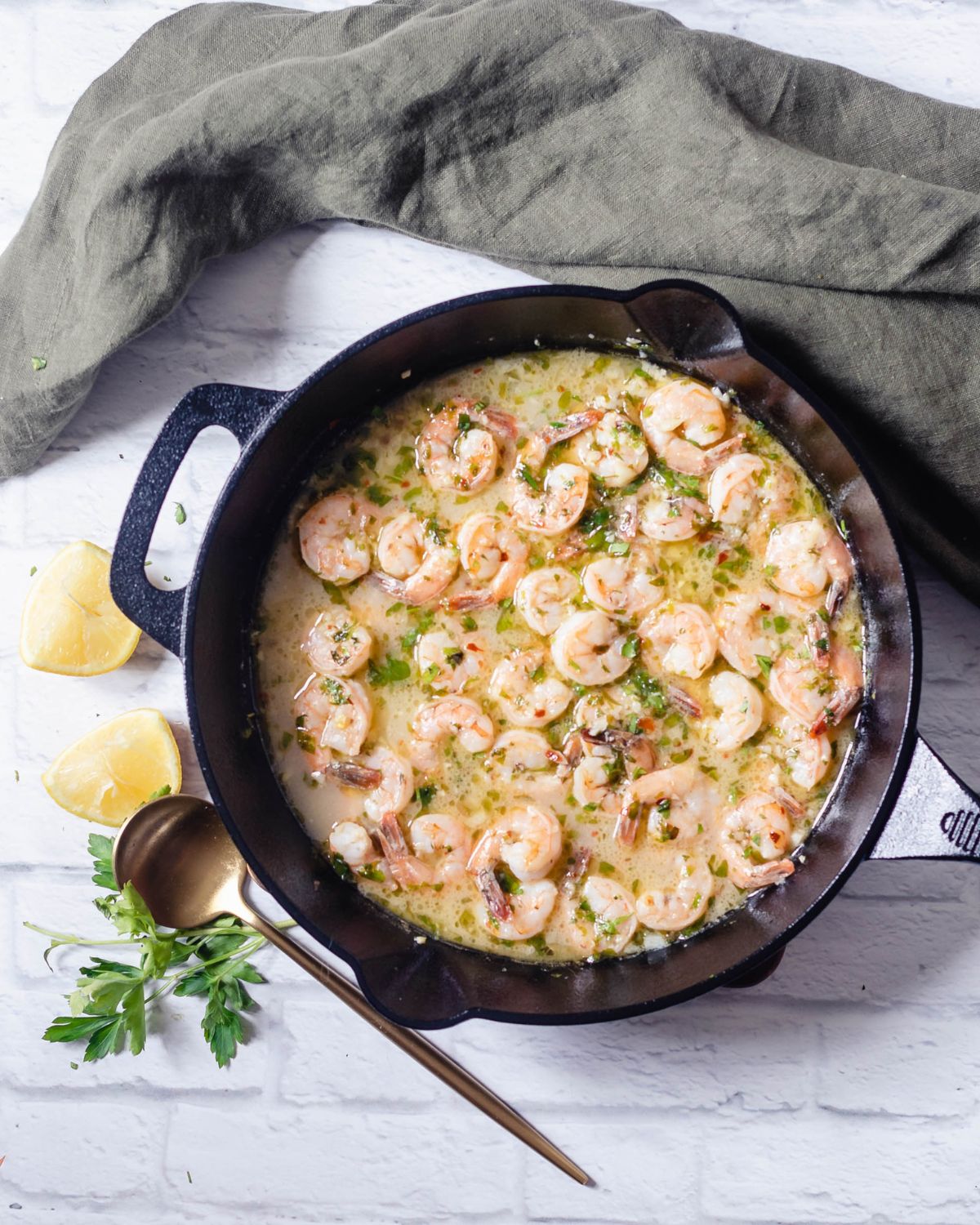 A cast iron pan with shrimp sauteed in wine and lemon juice for an easy scampi recipe. 