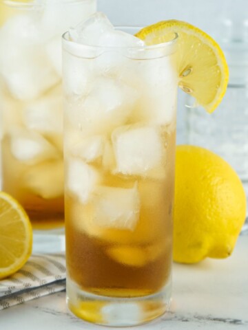 A long island iced tea beverage in a tall glass with ice.