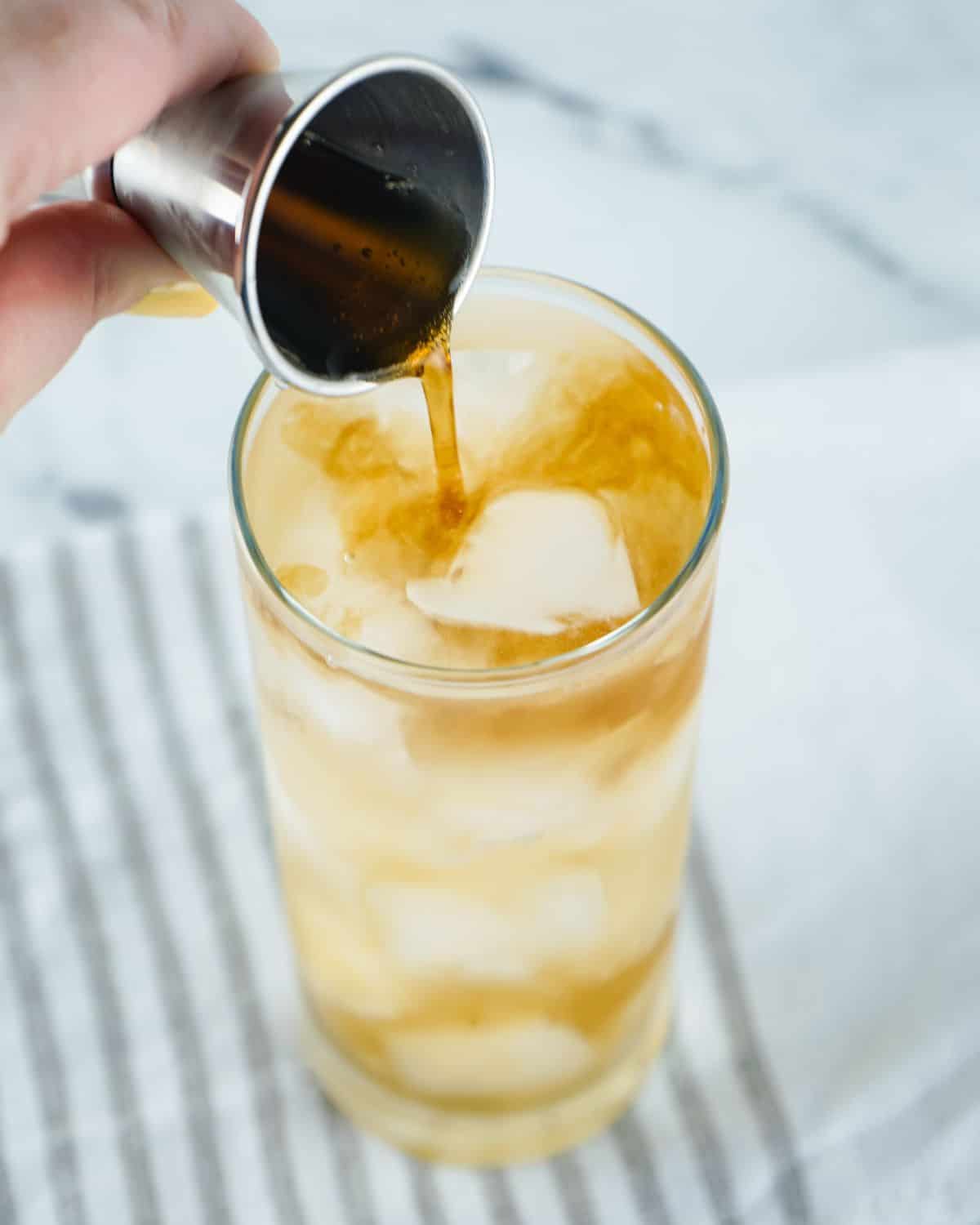 Long island iced tea with coke being poured to top off the drink.