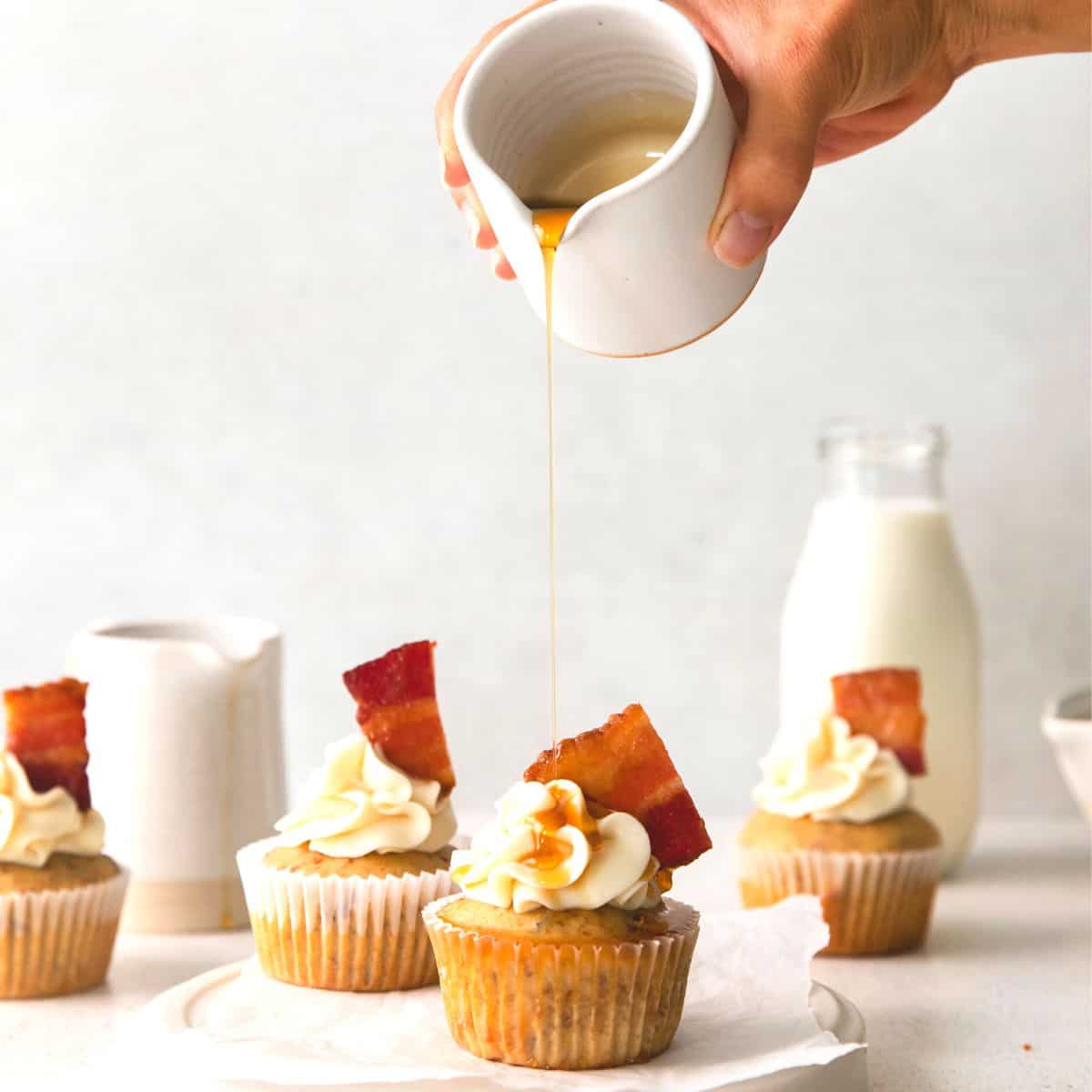 Maple syrup being drizzled on maple bacon cupcakes. 